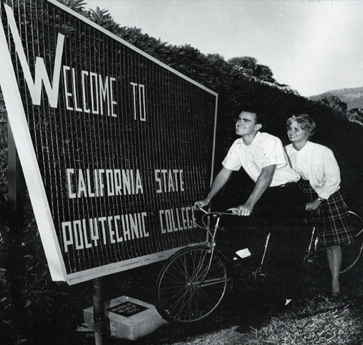 Two students on a tandem bicycle near the Cal Poly entrance