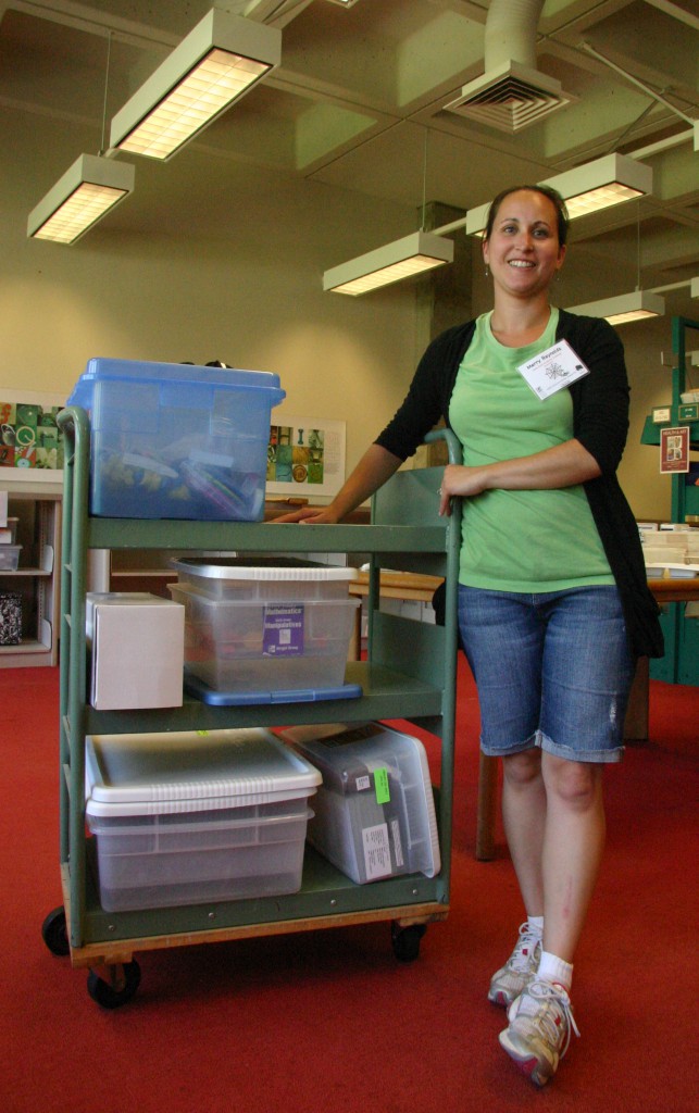 Photo of teacher with science kits and storage bins from Kennedy Library.