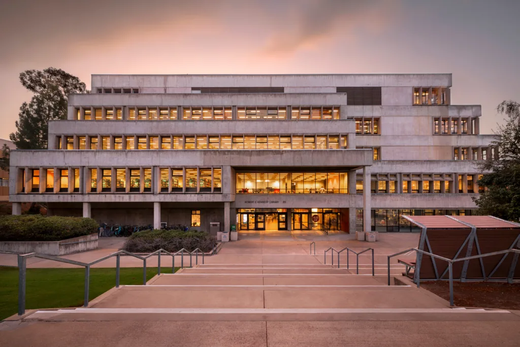 Robert E. Kennedy Library entrance, at twilight, with the interior lights on.